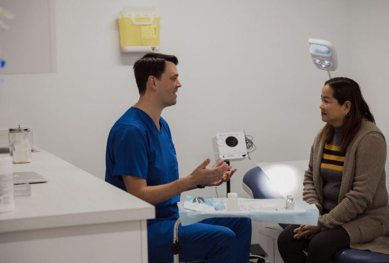 Doctor talking with a patient. Both are smiling.